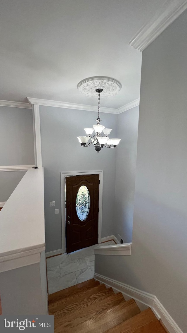 entryway featuring crown molding, a chandelier, and baseboards