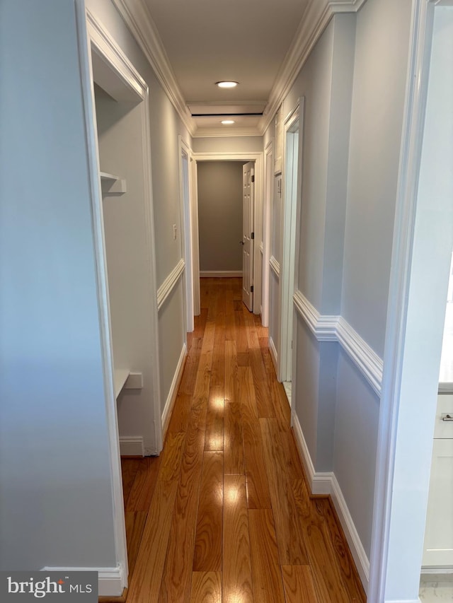 hall with light wood-style floors, ornamental molding, and recessed lighting