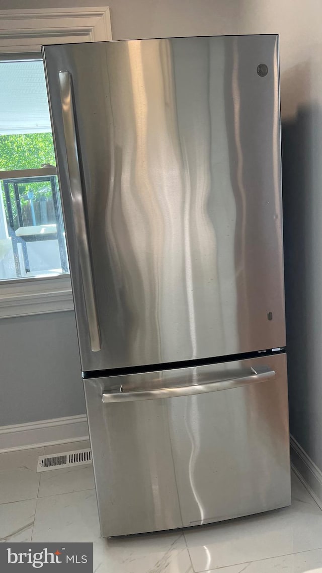 detailed view of freestanding refrigerator and baseboards