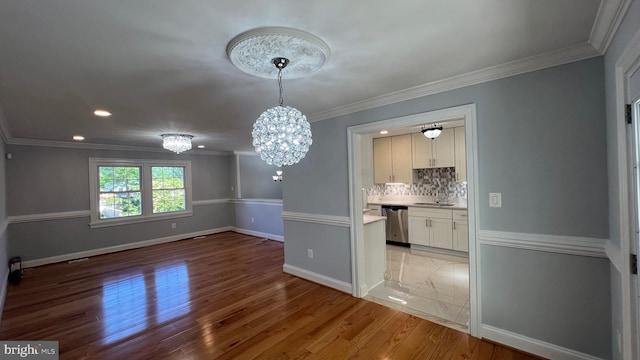 unfurnished dining area featuring light wood-style flooring, a chandelier, baseboards, crown molding, and recessed lighting