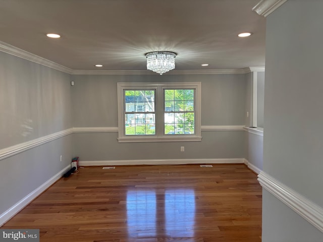 empty room featuring a chandelier, recessed lighting, wood finished floors, ornamental molding, and baseboards