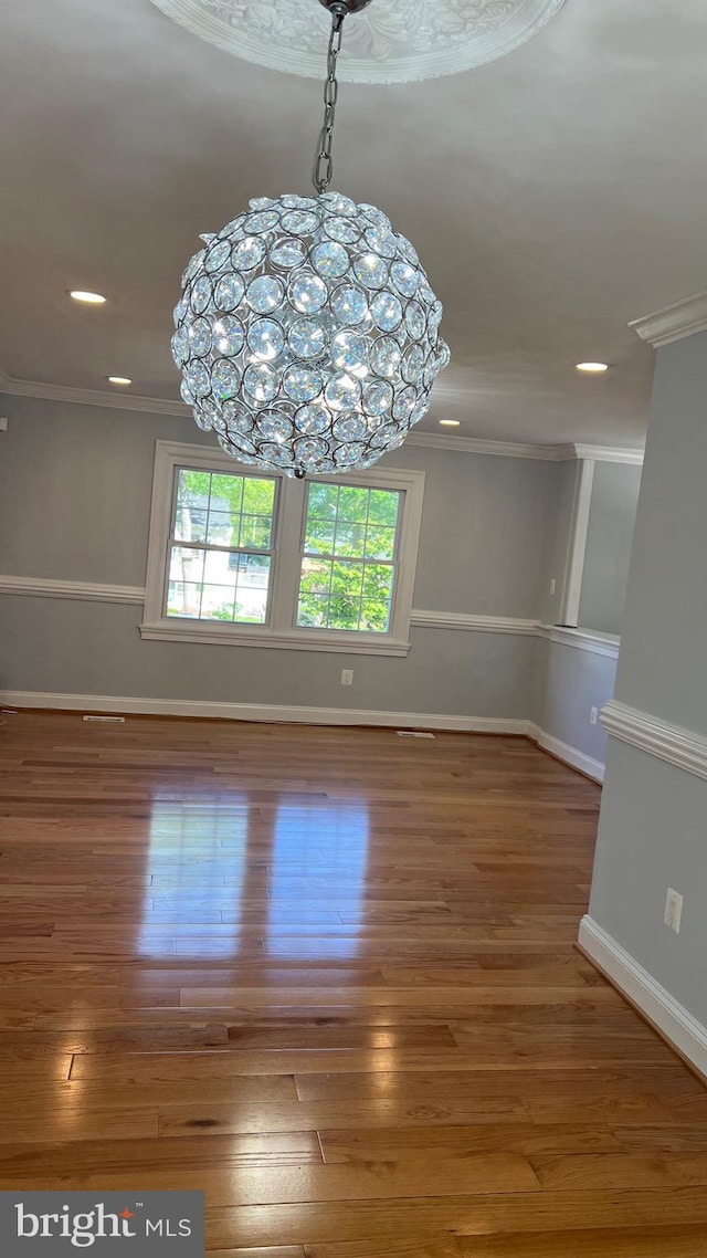 unfurnished dining area with crown molding, baseboards, recessed lighting, wood finished floors, and a chandelier