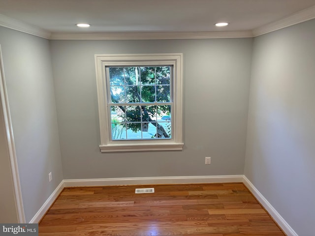 empty room with ornamental molding, light wood-style flooring, baseboards, and recessed lighting