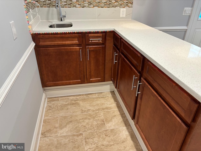 bar with tasteful backsplash, a sink, and stone finish flooring