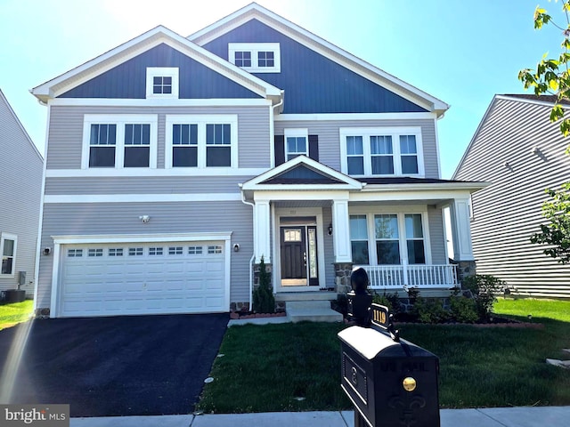 view of front of home featuring an attached garage, a porch, driveway, and a front yard