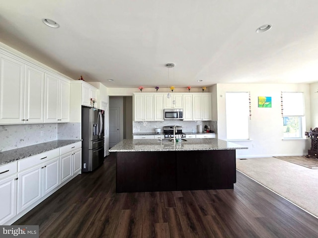 kitchen with appliances with stainless steel finishes, decorative backsplash, white cabinetry, a sink, and dark wood-type flooring