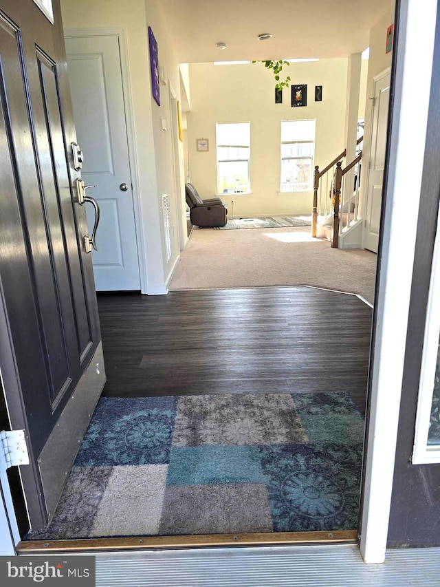 hall with wood finished floors, stairs, carpet, and baseboards