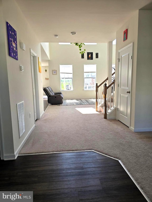 corridor featuring baseboards, stairs, carpet floors, and wood finished floors
