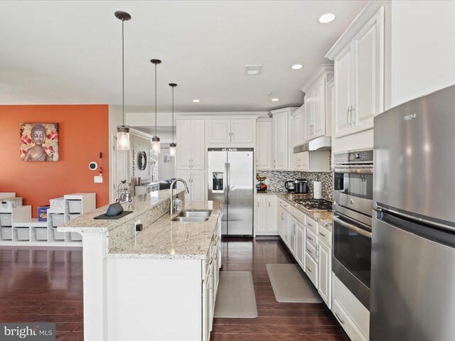 kitchen with appliances with stainless steel finishes, a sink, dark wood finished floors, white cabinetry, and recessed lighting