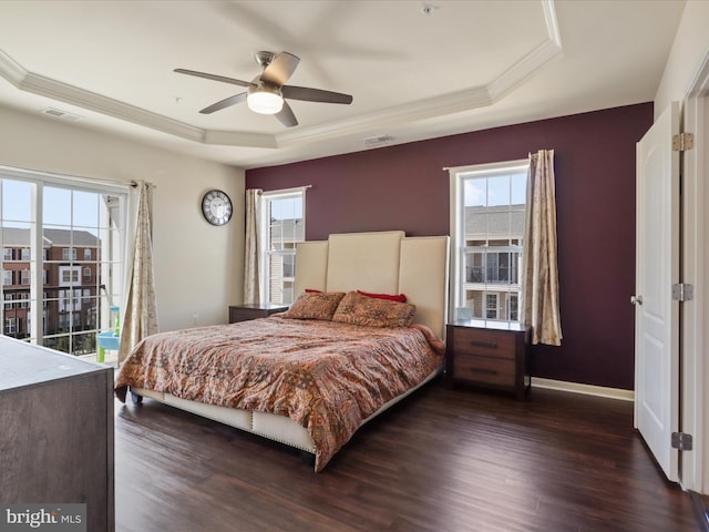 bedroom featuring a tray ceiling, dark wood-style floors, ornamental molding, baseboards, and ceiling fan