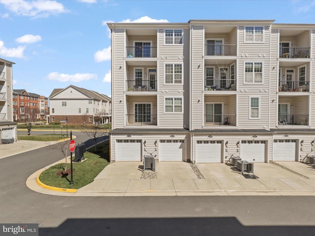 view of building exterior featuring driveway, an attached garage, a residential view, and cooling unit