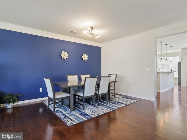 dining room featuring a chandelier, ornamental molding, wood finished floors, and baseboards