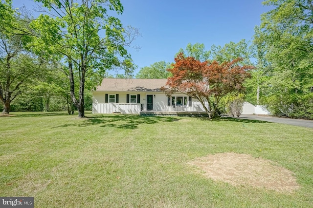ranch-style house featuring covered porch, a front lawn, and driveway