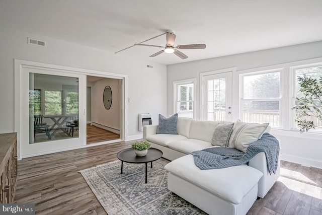 living room featuring a baseboard heating unit, heating unit, healthy amount of natural light, and a ceiling fan