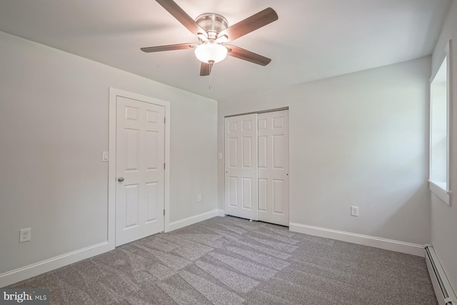 unfurnished bedroom with a baseboard heating unit, carpet floors, baseboards, a closet, and a ceiling fan