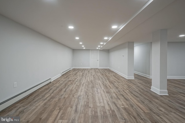 finished below grade area with a baseboard radiator, a baseboard heating unit, wood finished floors, recessed lighting, and baseboards