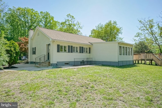 rear view of house featuring a chimney, a lawn, a wooden deck, and stairs