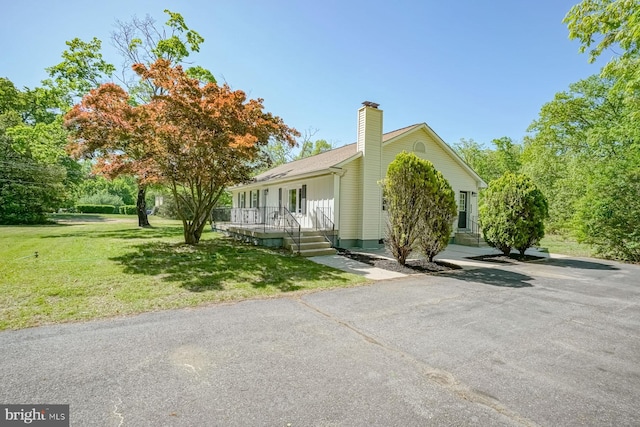 view of home's exterior with a lawn, a chimney, and covered porch