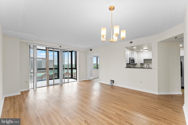 24 Courthouse Sq Unit 710, Rockville, MD 20850 - unfurnished living room featuring a chandelier, light wood-type flooring, and baseboards