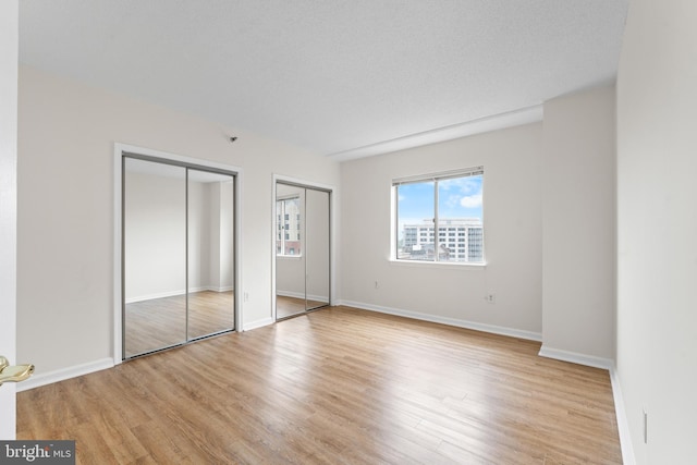 24 Courthouse Sq Unit 710, Rockville, MD 20850 - unfurnished bedroom featuring multiple closets, light wood-type flooring, and baseboards