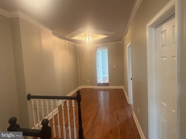 hallway with wood finished floors, baseboards, ornamental molding, and an upstairs landing