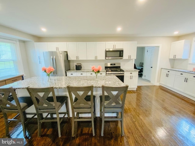 239 Glentay Ave, Lansdowne, PA 19050 - kitchen featuring appliances with stainless steel finishes, light stone countertops, white cabinets, wood finished floors, and a kitchen island