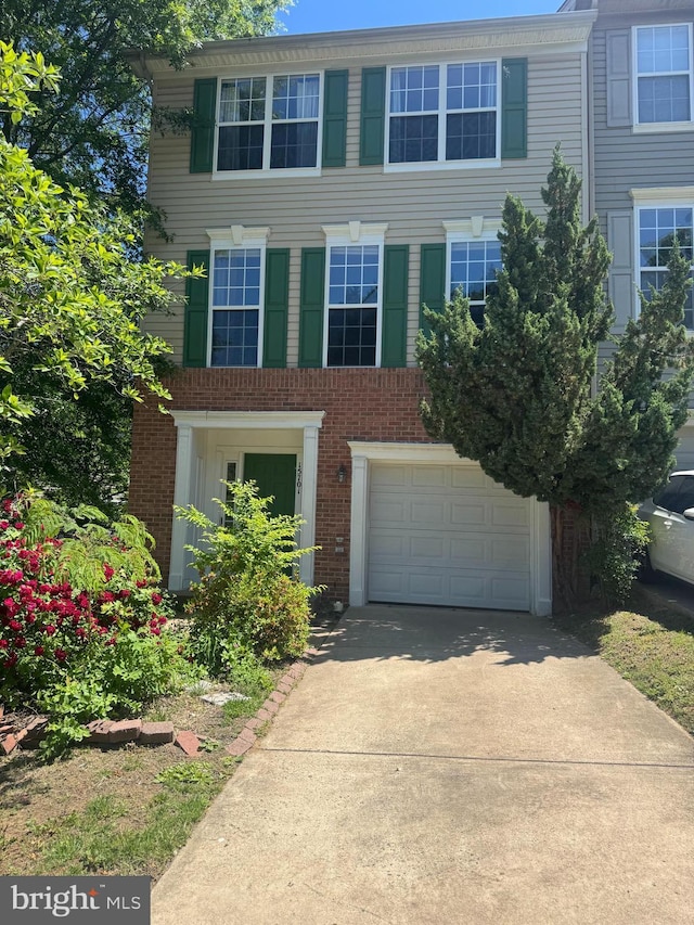 view of front of home featuring an attached garage, concrete driveway, and brick siding