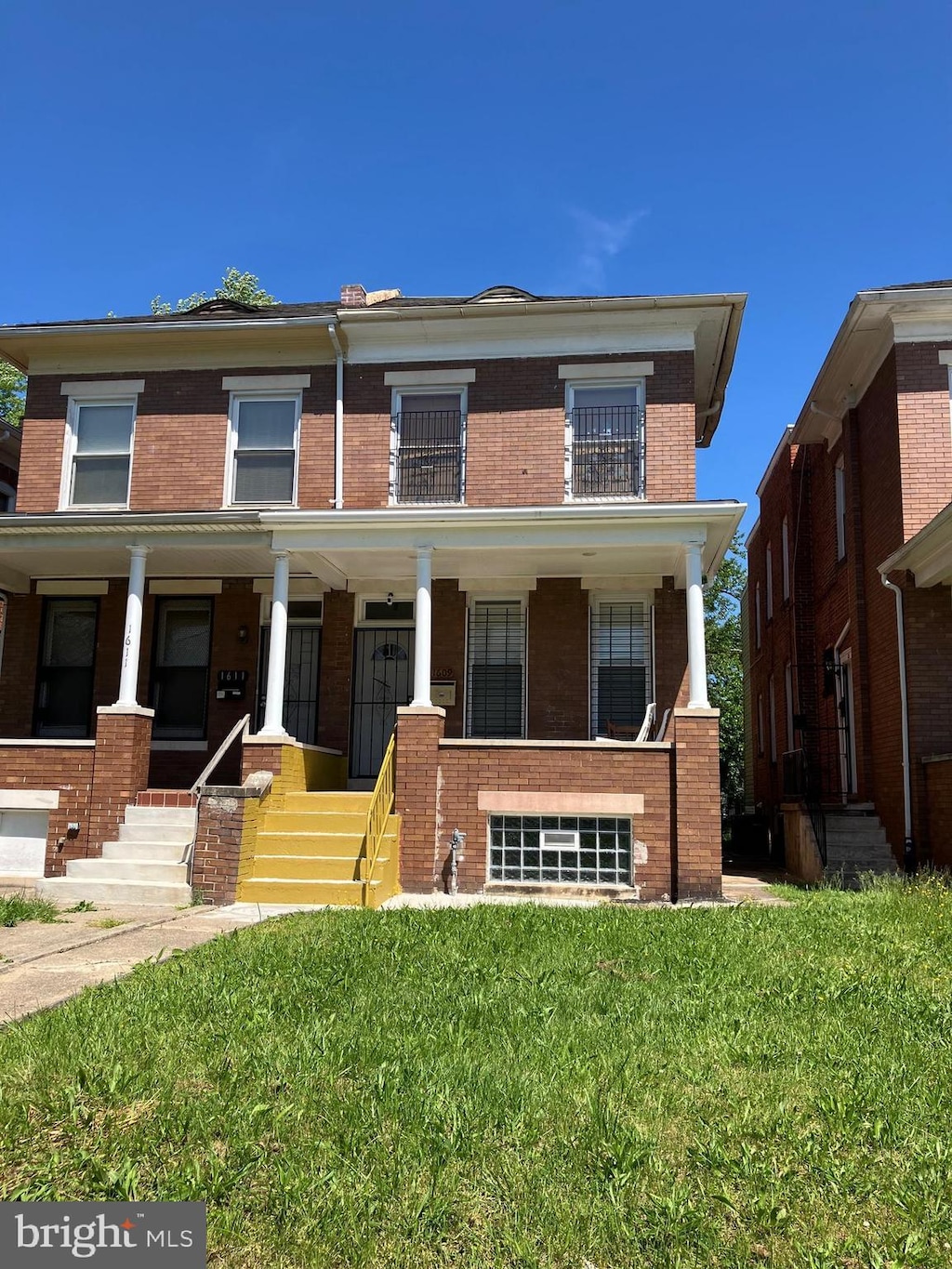 view of front of home with brick siding, covered porch, and a front yard