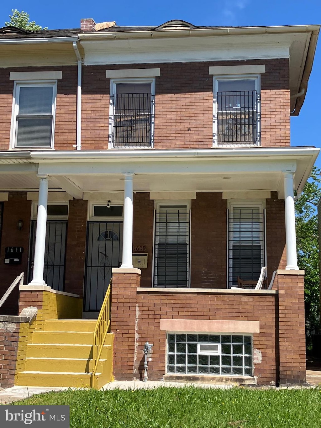 view of front facade featuring covered porch, brick siding, and a balcony