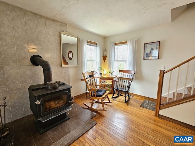 419 Camden St, Dillwyn, VA 23936 - living area with wood-type flooring, a wood stove, stairs, a textured ceiling, and baseboards