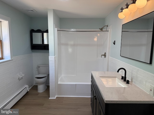 full bathroom with a baseboard heating unit, wainscoting, tile walls, toilet, and wood finished floors