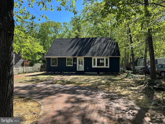 new england style home with fence and roof with shingles