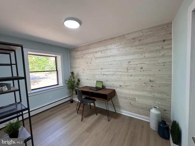 office area featuring baseboard heating, wood finished floors, wood walls, and baseboards