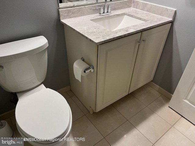 bathroom featuring toilet, vanity, tile patterned flooring, and baseboards