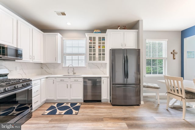 kitchen with appliances with stainless steel finishes, a sink, light wood-style flooring, plenty of natural light, and recessed lighting