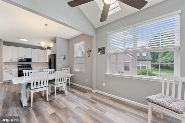 dining space featuring a ceiling fan, light wood-style floors, baseboards, lofted ceiling, and a chandelier