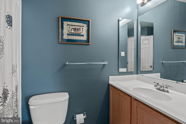 full bath featuring toilet, vanity, and a shower with curtain