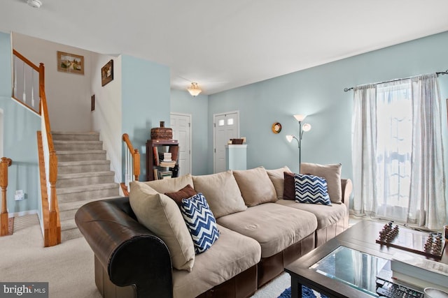 living room featuring stairs, healthy amount of natural light, and light colored carpet