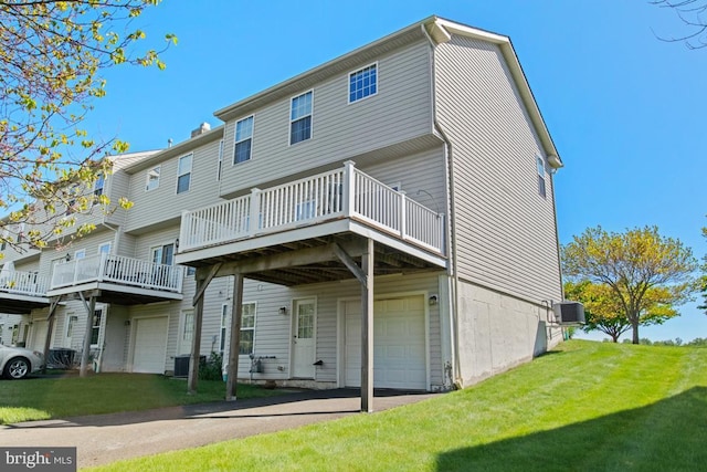 back of property featuring a garage, a lawn, cooling unit, and asphalt driveway