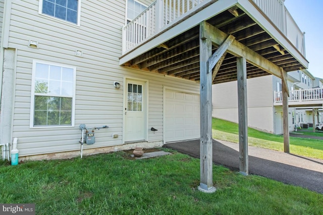 view of exterior entry with a garage, asphalt driveway, and a yard
