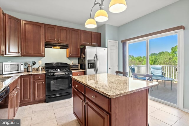 kitchen featuring black appliances, under cabinet range hood, light stone countertops, and decorative light fixtures