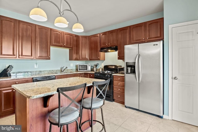 kitchen featuring black appliances, under cabinet range hood, a kitchen breakfast bar, light tile patterned flooring, and a kitchen island