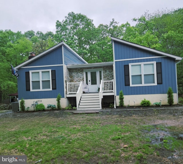mid-century modern home featuring a wooden deck, a front yard, stairway, cooling unit, and view of wooded area
