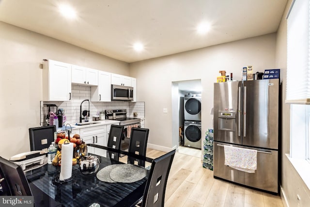 743 Cherry St, Camden, NJ 08103 - kitchen with appliances with stainless steel finishes, stacked washing machine and dryer, a sink, backsplash, and light wood-style floors