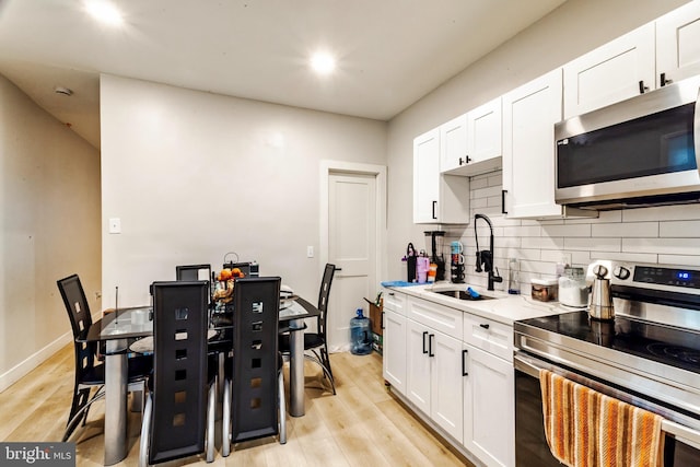 743 Cherry St, Camden, NJ 08103 - kitchen featuring stainless steel appliances, a sink, backsplash, white cabinetry, and light wood-style floors