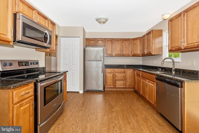 11005 Horseshoe Dr, Frederick, MD 21701 - kitchen featuring stainless steel appliances, a sink, light wood-style floors, brown cabinetry, and dark stone countertops