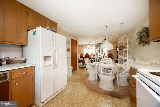 kitchen with white appliances, light countertops, brown cabinets, light floors, and pendant lighting