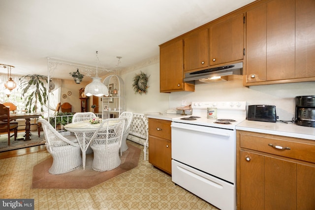 kitchen with electric range, under cabinet range hood, light countertops, and brown cabinets