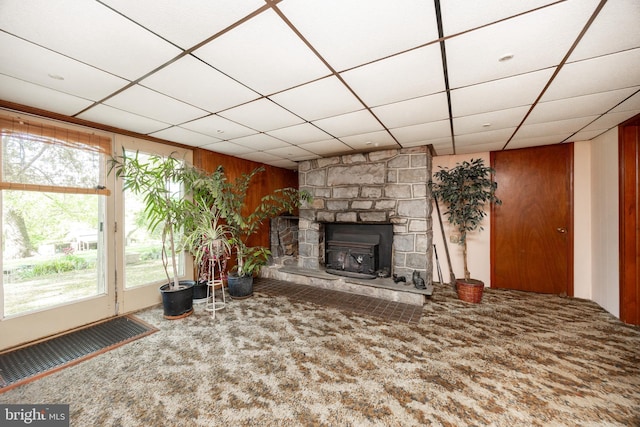 unfurnished living room with carpet flooring, wooden walls, and a drop ceiling