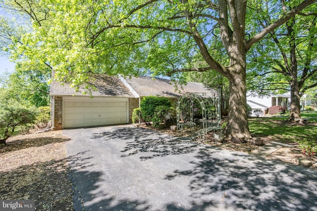 obstructed view of property featuring asphalt driveway and brick siding